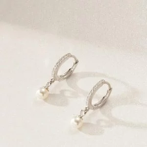 Sterling Silver Diamante Pearl Earrings flat down on a shiny, glittery surface.